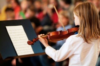Girls plays violin for a small audience.